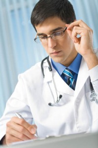 Doctor with stethoscope writing at office