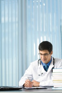 Happy young doctor or student writing at office